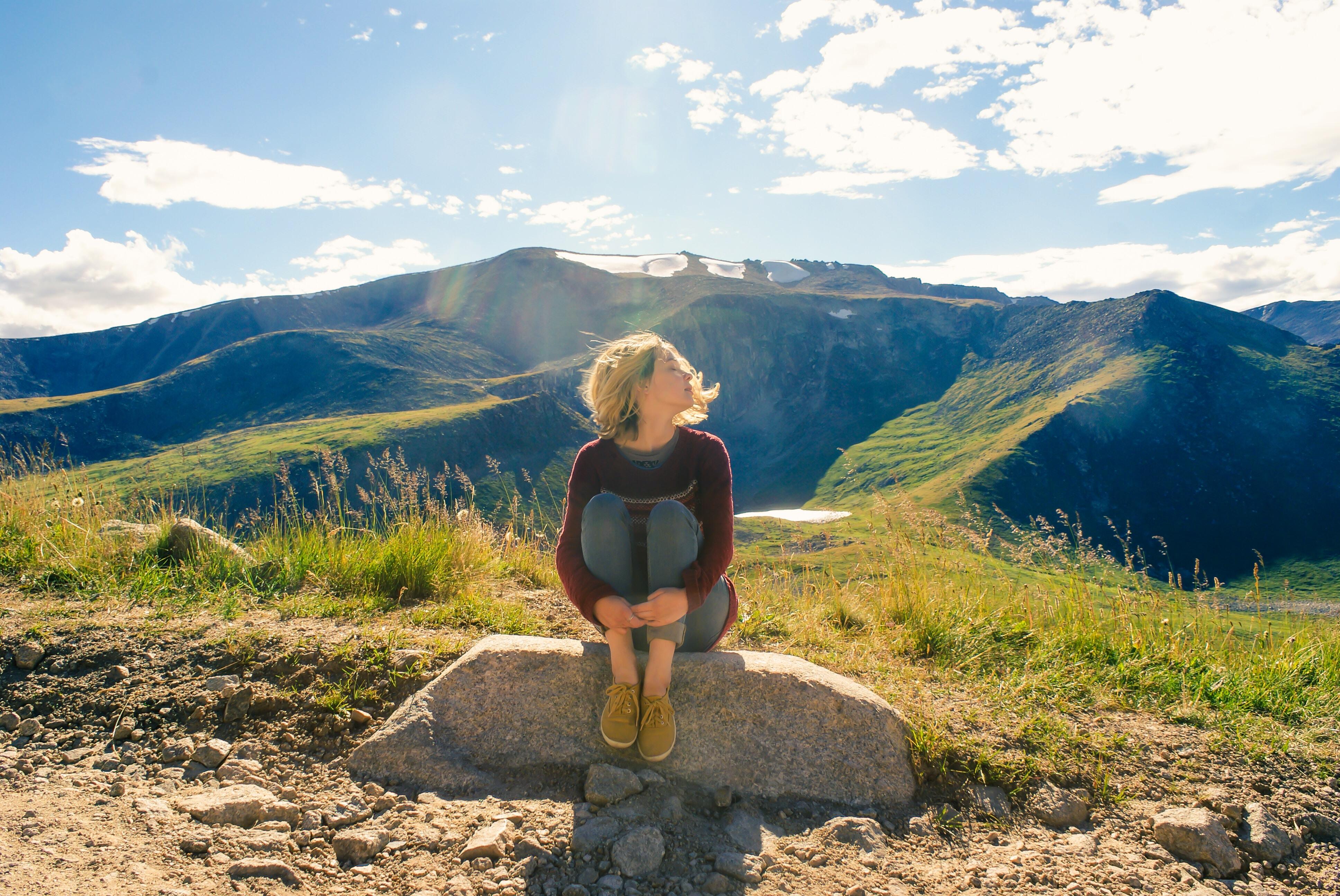 A woman sitting on a rock overlooking mountains